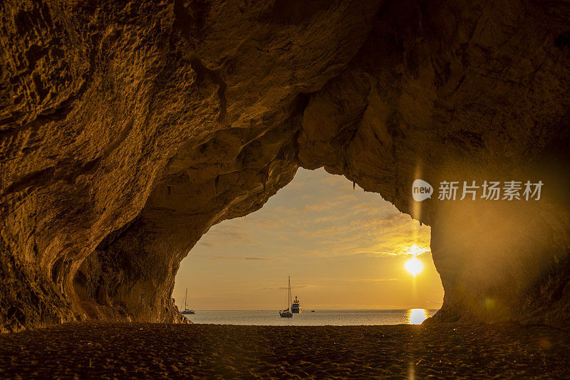 意大利撒丁岛的奥罗塞湾，Cala Luna洞穴，夕阳下，背景是帆船。